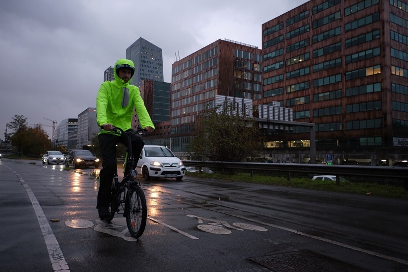 mężczyzna jadący rowerem, który ma na sobie jasno zieloną kurtkę rowerową