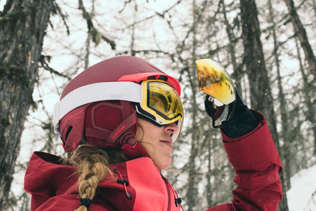 kobieta w kasku narciarskim trzymająca gogle