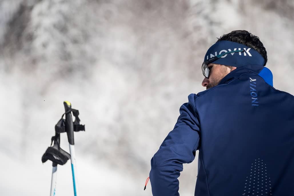 mężczyzna w stroju sportowym z kijkami narciarskimi