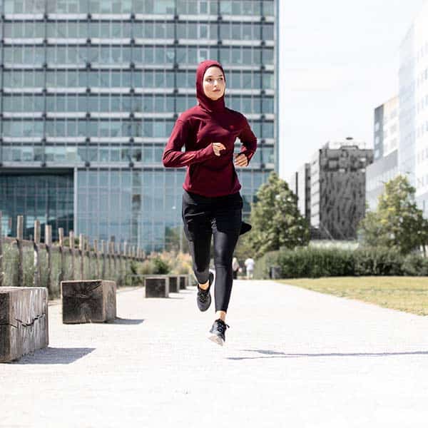 kobieta w bluzie z kapturem uprawia jogging w mieście