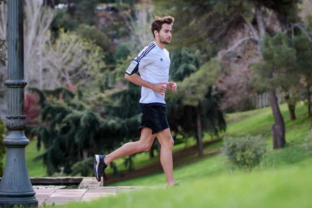 mężczyzna biegnący w krótkich spodenkach i koszulce do biegania w parku