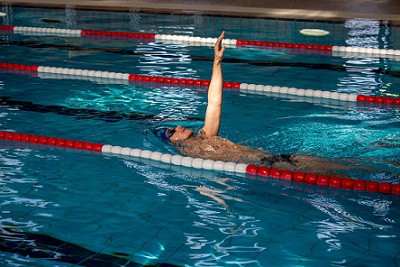 mężczyzna pływający na plecach w basenie sportowym