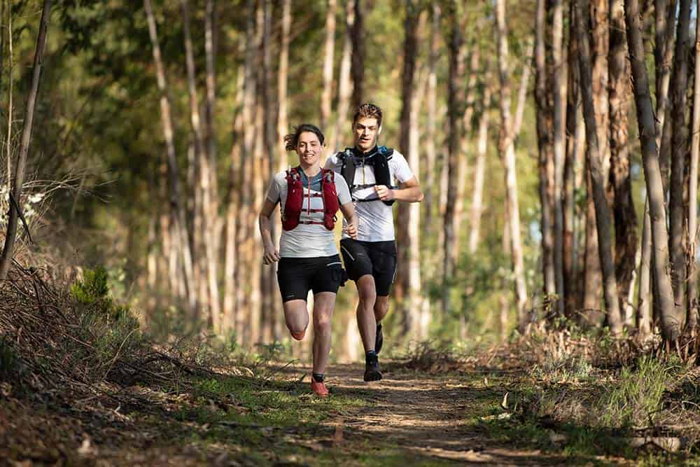kobieta i mężczyzna biegną przez las w strojach do biegania 