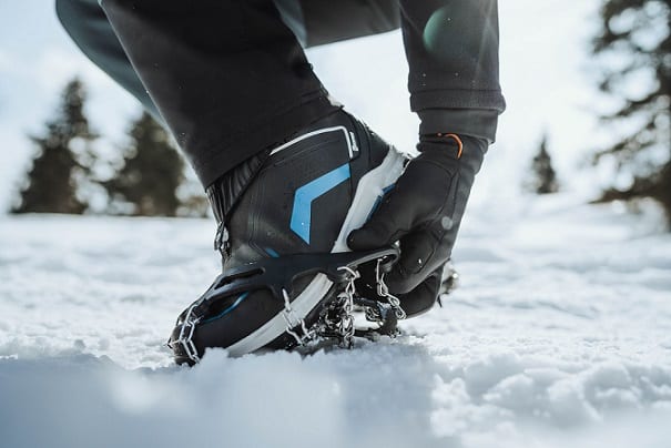 osoba ściągająca raczki z butów na śniegu