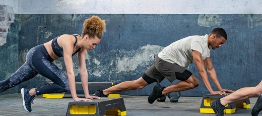 kobieta i mężczyzna w strojach sportowych ćwiczący z podestem do aerobiku