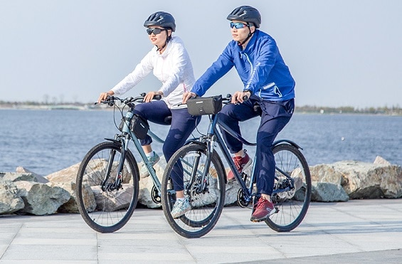 kobieta i mężczyzna w kaskach i okularach przeciwsłonecznych jadący na rowerach