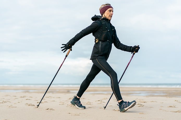 kobieta w stroju sportowym i opasce na włosach trenująca z kjami do nordic walking