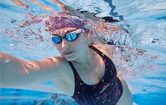 kobieta płynąca pod wodą w czepku i okularach pływackich