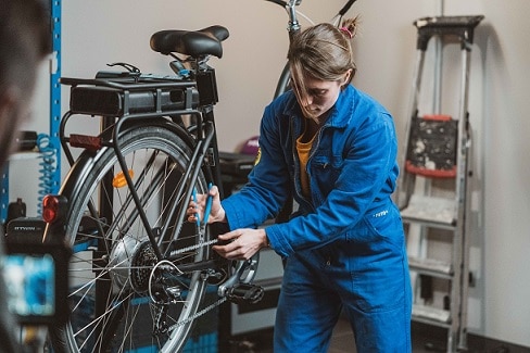 kobieta naprawiająca łańcuch rowerowy