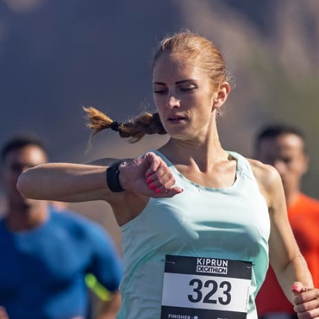 kobieta w stroju do biegania patrzy na swój zegarek sportowy
