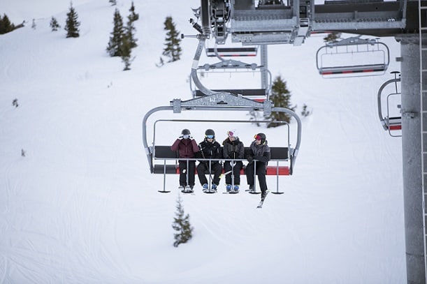 ludzie jadący kolejką krzesełkową na stoku narciarskim
