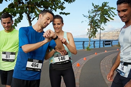mężczyźni w strojach do biegania z kobietą patrzącą na zegarek sportowy
