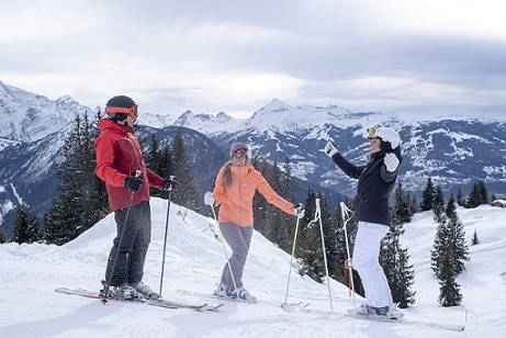 Kobiety i mężczyzna stojący na nartach z kijkami narciarskimi na stoku