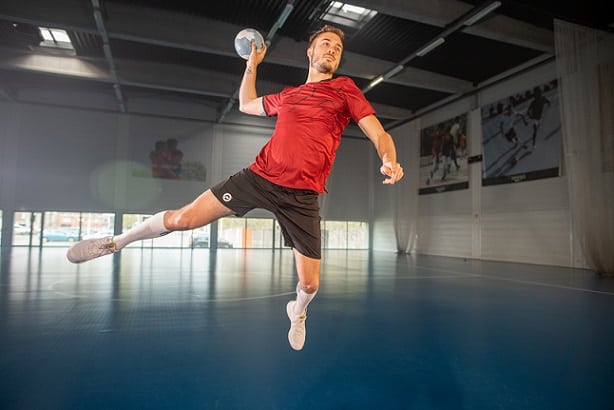 mężczyzna skaczący w stroju sportowym trzymający piłkę do gry w piłkę ręczną