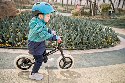 dziecko w kasku rowerowym na rowerku biegowym
