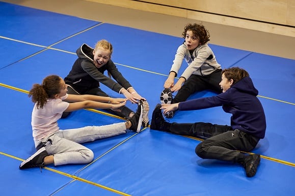dzieci wykonujące ćwiczenia gimnastyczne w odzieży sportowej