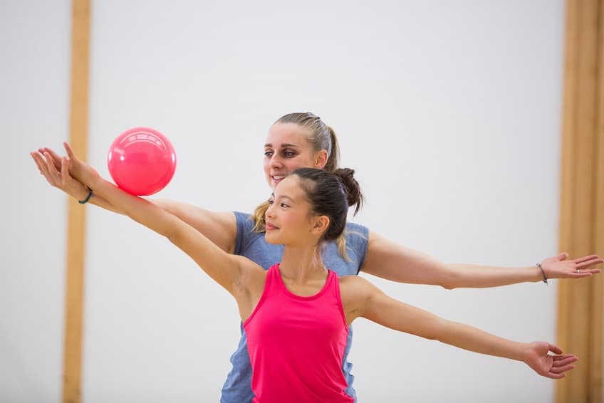 kobieta i dziewczynka trenujące gimnastykę artystyczną z piłką gimnastyczną